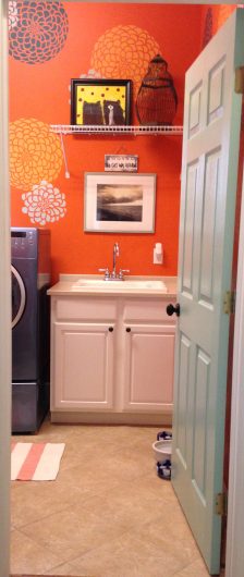 An orange laundry room stenciled with the Zinnia Grande Flower Stencil from Cutting Edge Stencils. http://www.cuttingedgestencils.com/flower-stencil-zinnia-wall.html