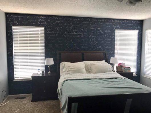 A navy blue stenciled bedroom accent wall using the French Poem Allover Stencil from Cutting Edge Stencils. http://www.cuttingedgestencils.com/french-typography-letter-wall-stencil.html