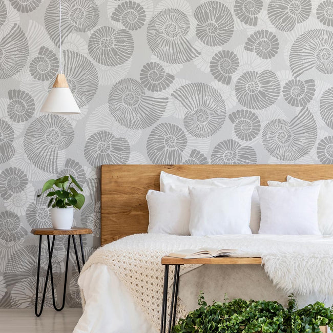 Bedroom with gray ammonite patterned stencils, wooden headboard, and white bedding.