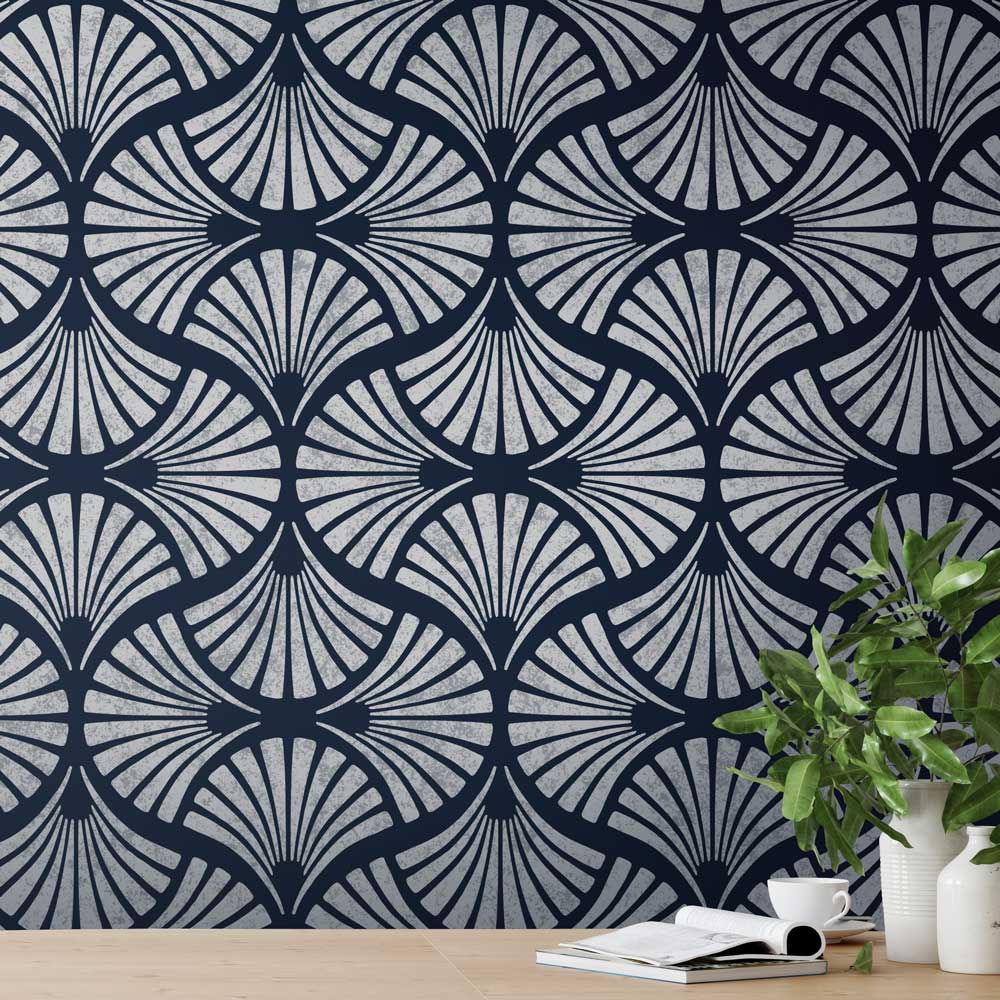 Navy blue and gray geometric stencil patterned wall with a plant and books on a wooden surface.