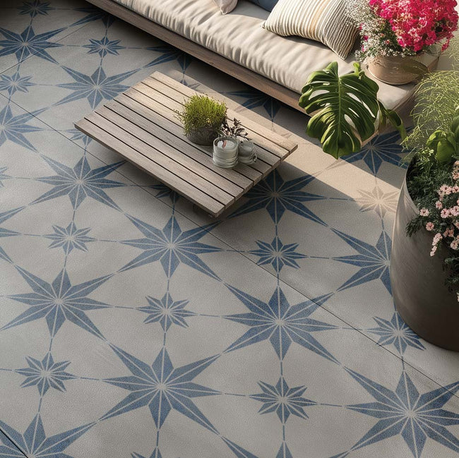 Outdoor cement patio with blue stenciled star-patterned floor, wooden table, and plants.