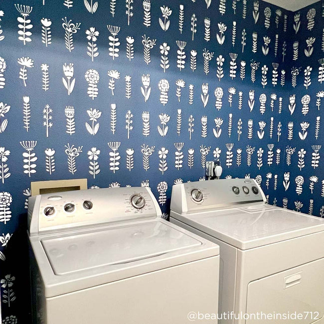white folk flowers stenciled on a blue laundry room wall