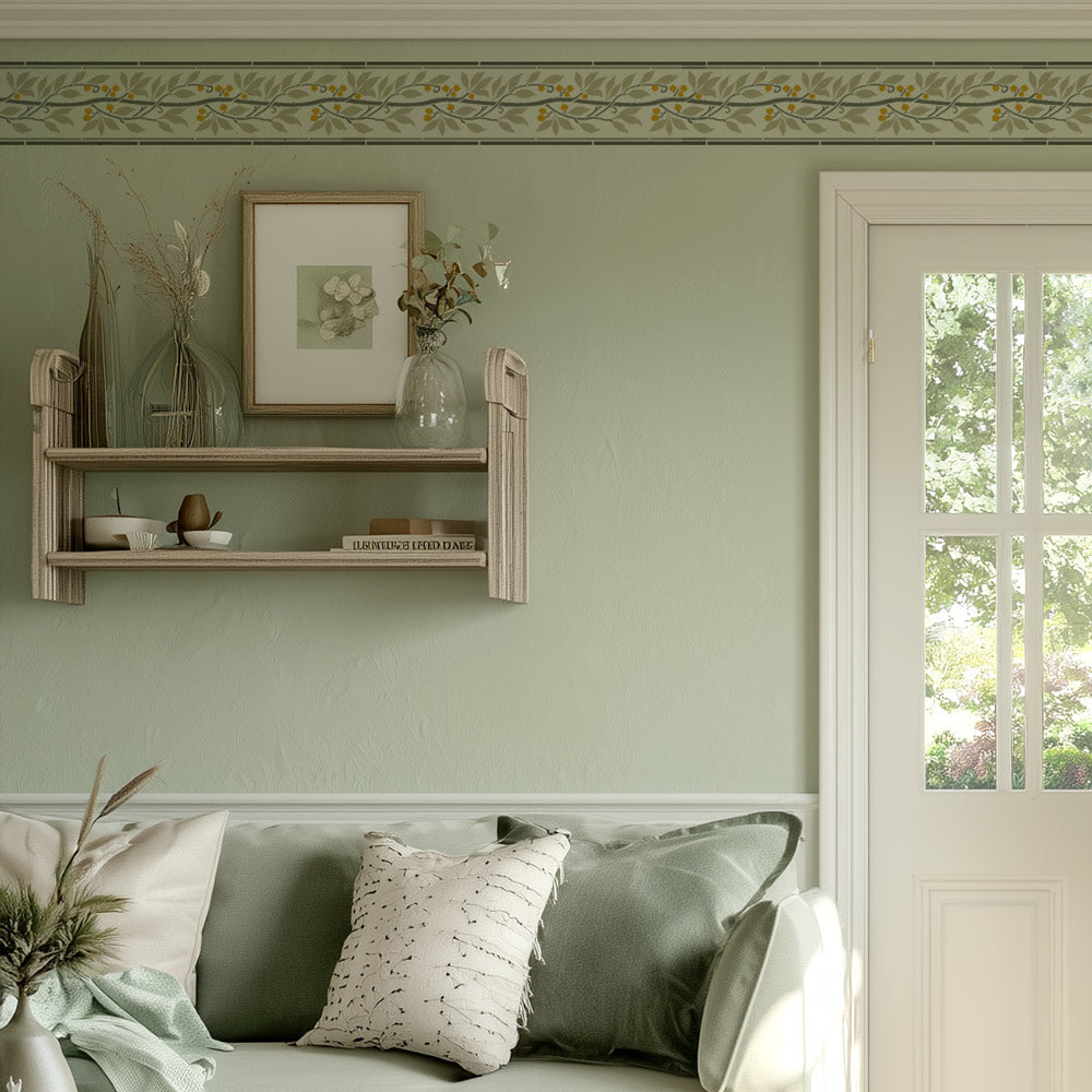 Stencil border with leaves on top of the living room wall with wooden shelf, framed picture, and decorative elements. top of wall bordered with a leaf stencil