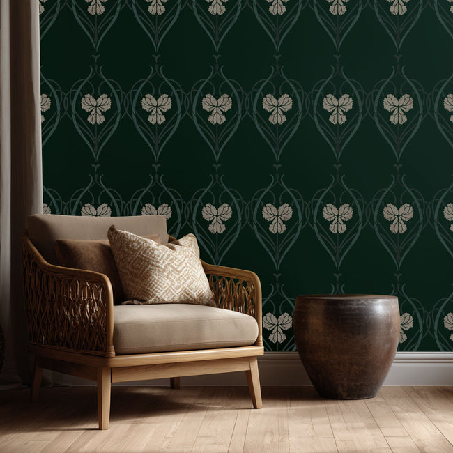Wicker chair with beige cushions against a dark green wall with floral stencil pattern