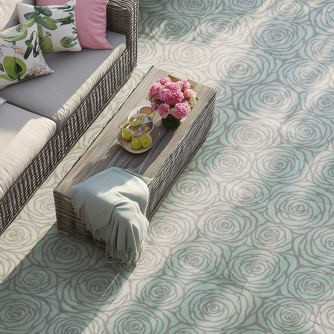Outdoor seating area with a wooden table, cushions, and a floral arrangement on a stenciled patterned patio with large rose stencil.