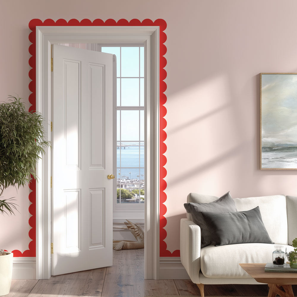 Living room with a white door, pink walls, and red scallop trim border around the moulding
