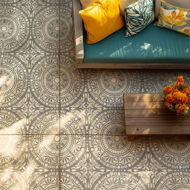Stenciled cement tiles on a floor with a wooden bench and colorful cushions.