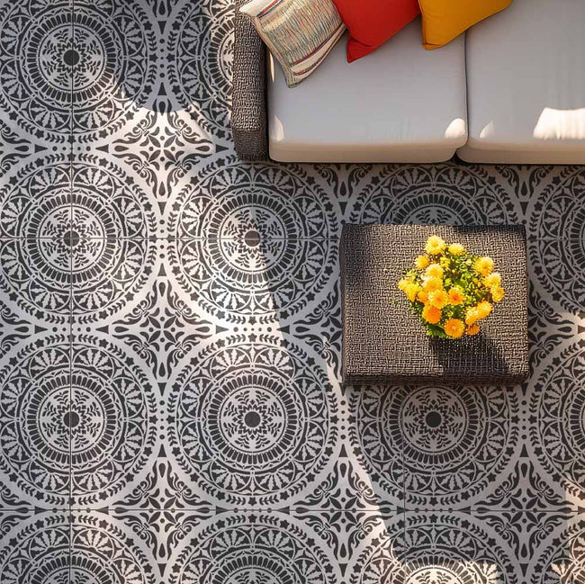 Patterned stenciled floor with a textured rug and colorful pillows on a concrete patio