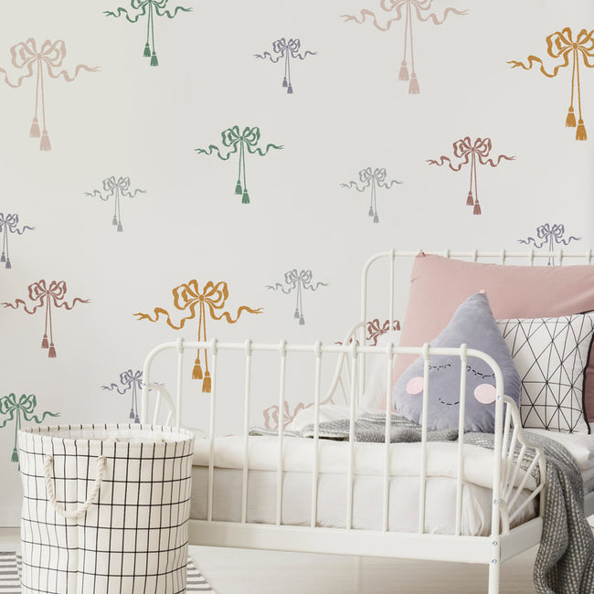 Children's room with white metal bed, patterned silk bow stencils, and storage basket.