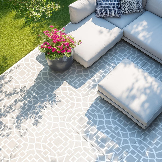 Outdoor seating area with a stenciled cement patio floor, white cushions, and a potted plant.