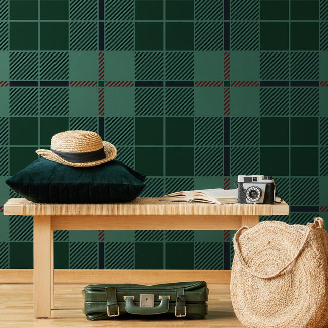 Wooden bench with a hat, bag, and camera against a green tartan stenciled plaid wall.