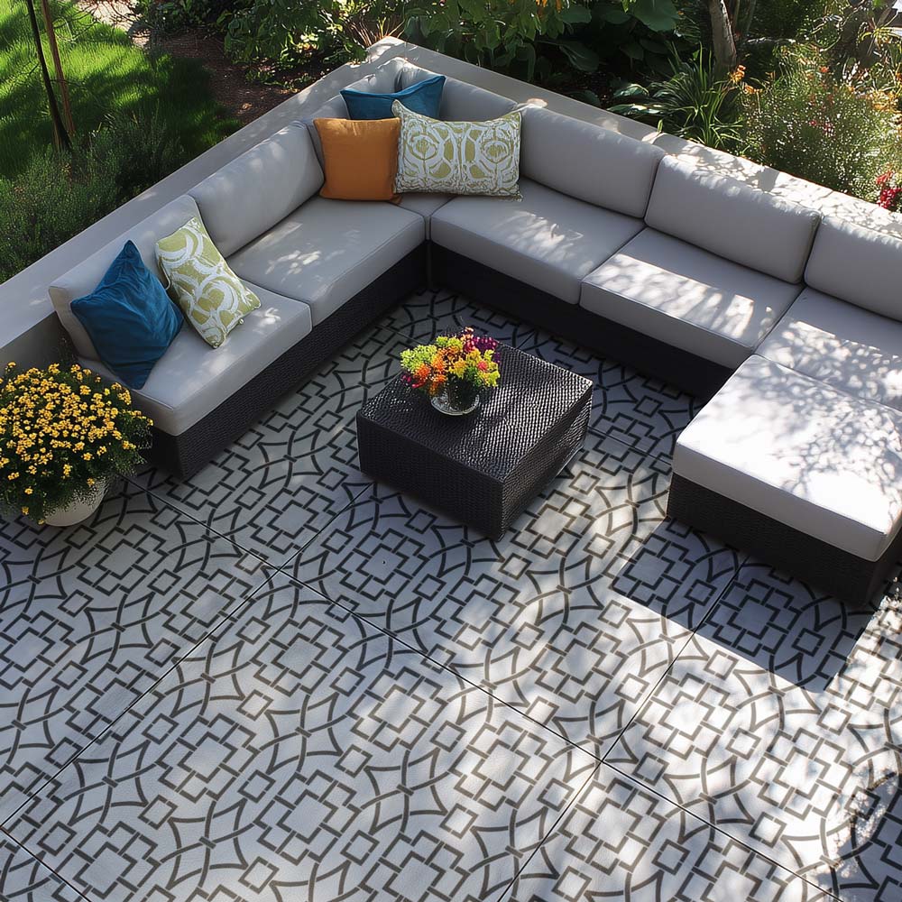 Outdoor cement patio with a sectional sofa, coffee table, and decorative pillows on a stenciled patterned patio floor.