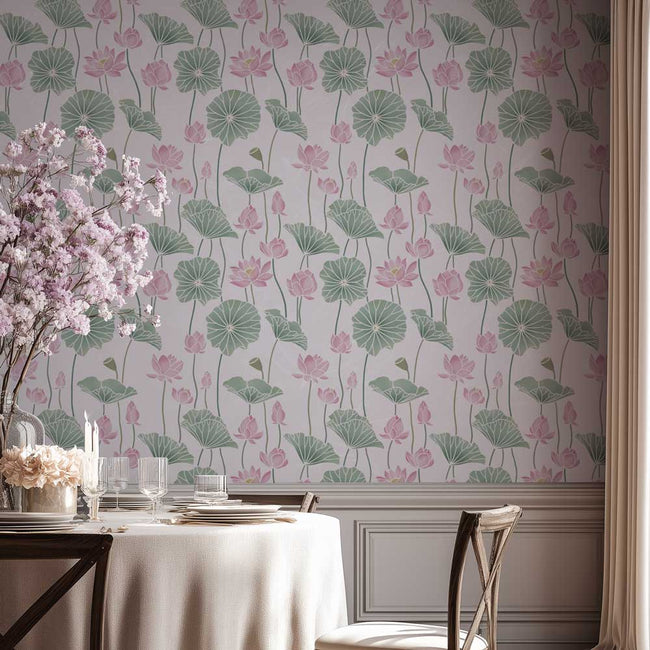 A dining room scene featuring a wall stencil with a repeating lotus pond pattern of pink lotus flowers and green lily pads on a pale lavender background. A white tablecloth, wooden chairs, and a vase of pink blossoms are arranged in the foreground.