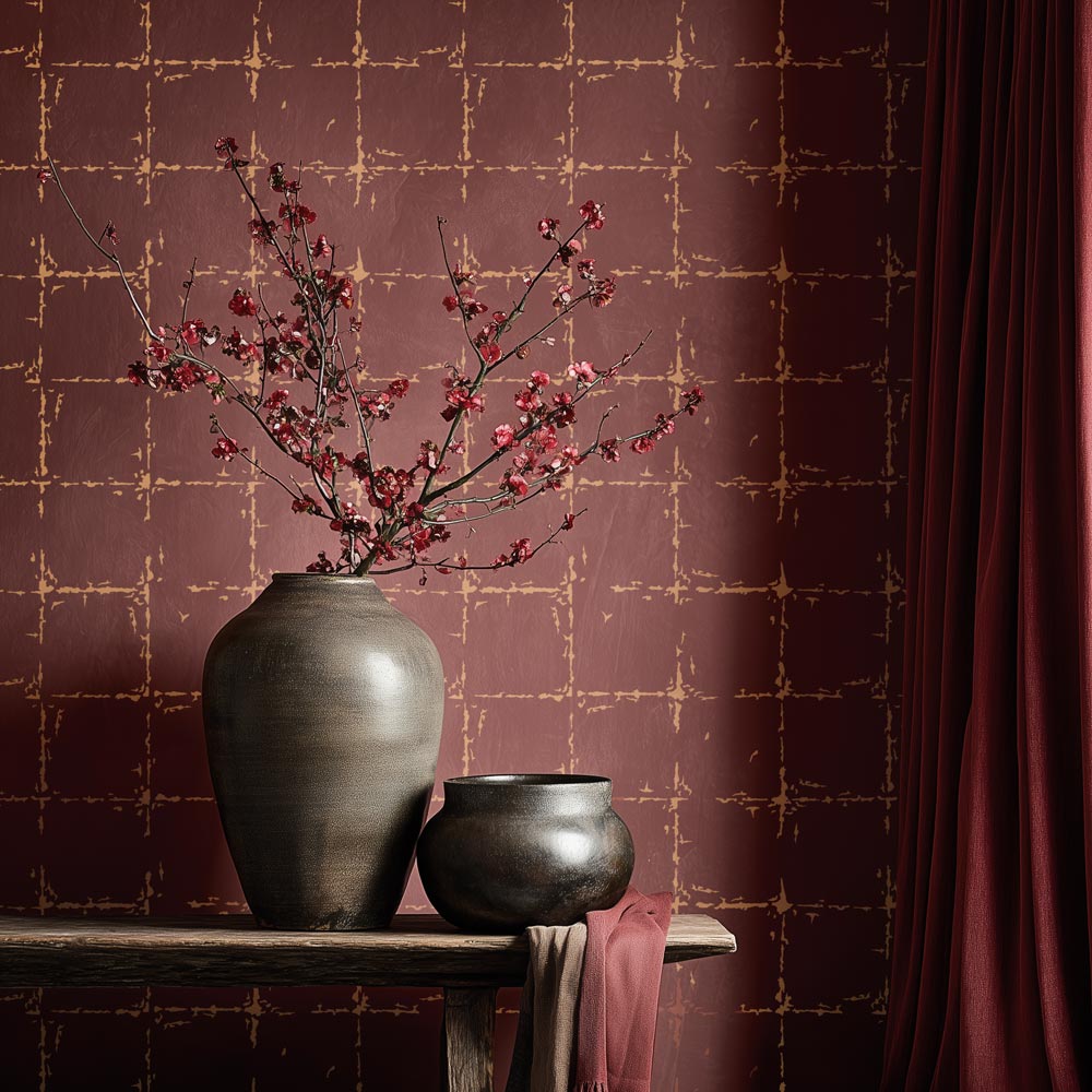 Two dark gray vases with branches and flowers on a wooden surface against a gold leaf stenciled patterned wall.