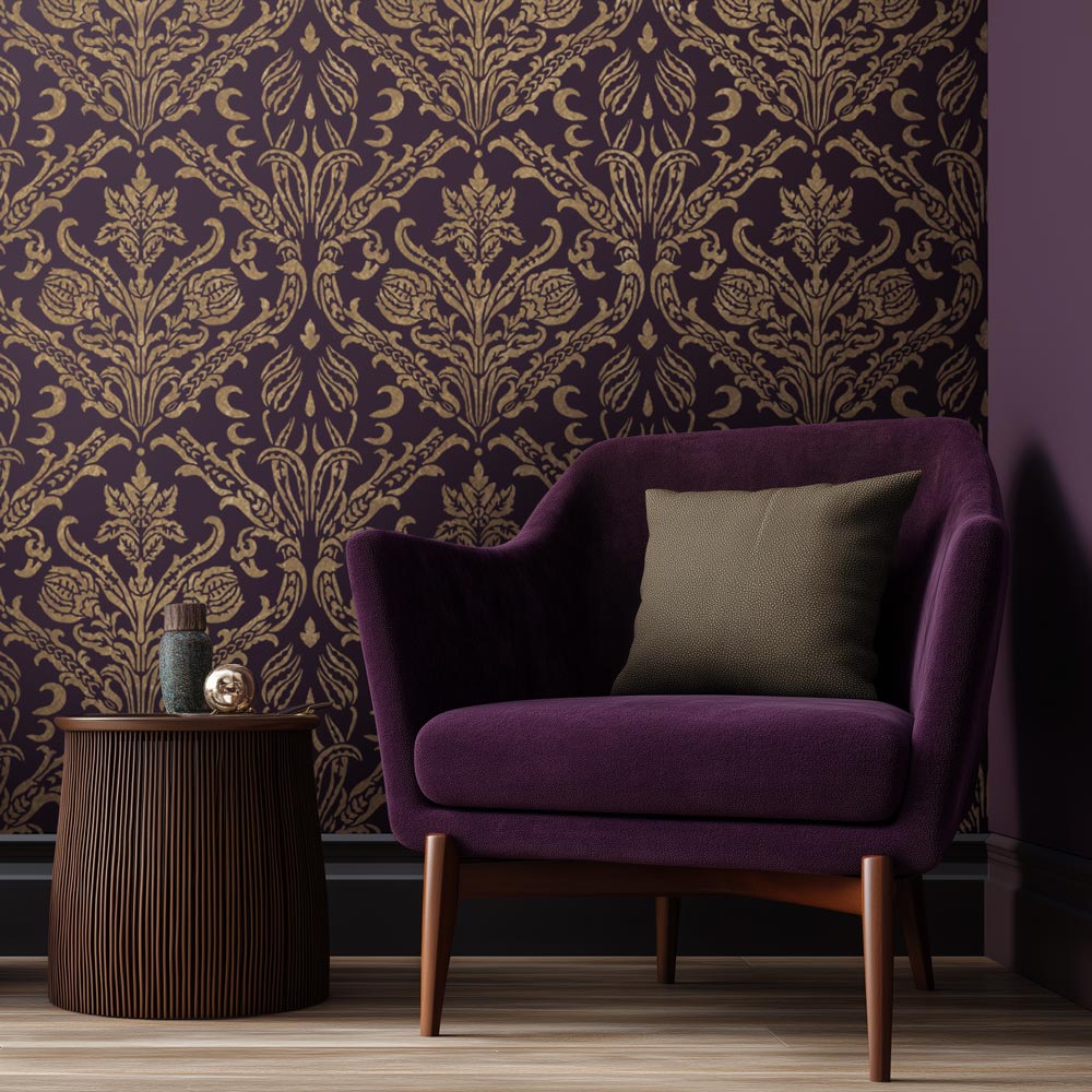 Purple armchair with a pillow against a decorative gold stenciled purple damask wall.