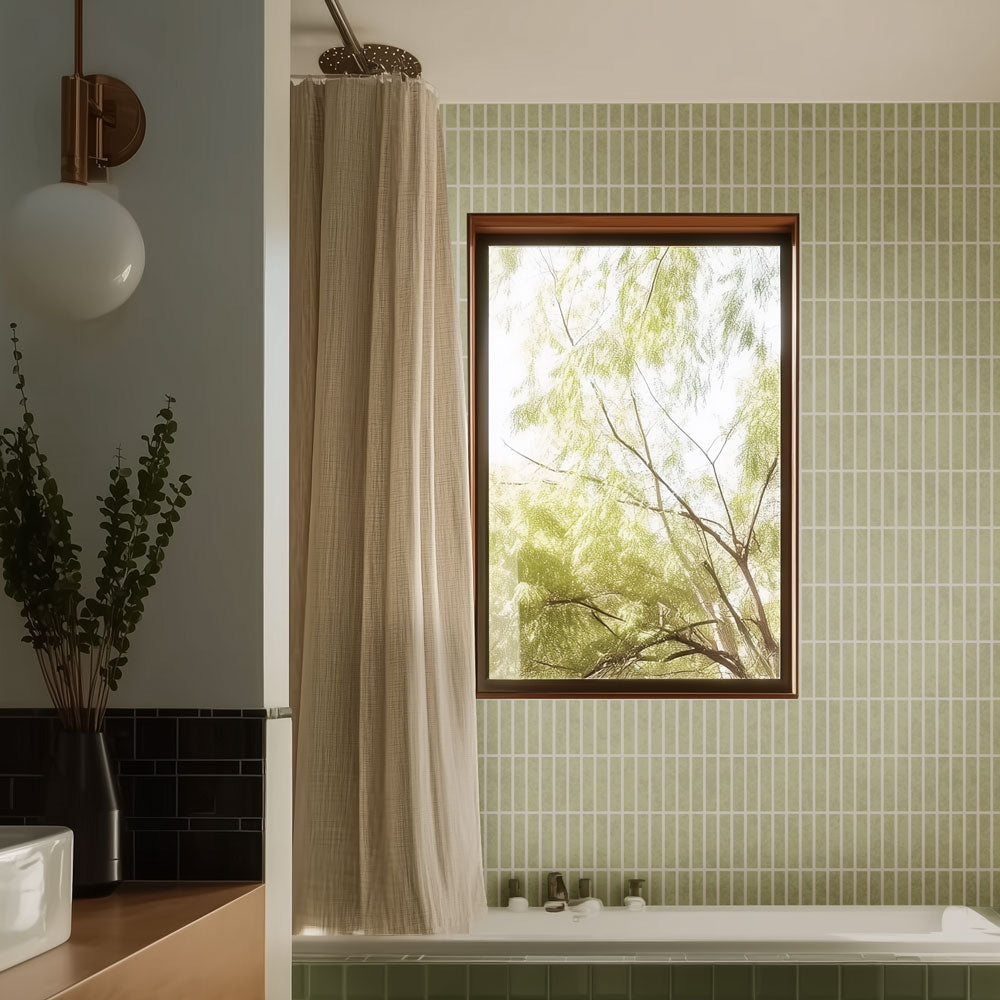 Bathroom with green stenciled tiled walls, a window, and a bathtub.