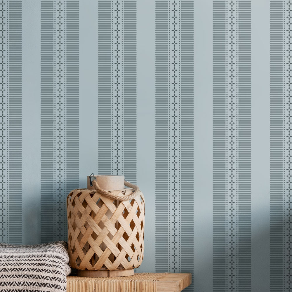 Woven basket on a wooden surface against a blue striped wall stencil background