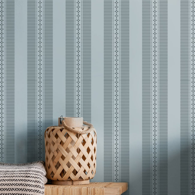 Woven basket on a wooden surface against a blue striped wall stencil background