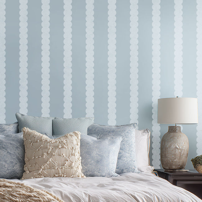 Bedroom with striped wall stencil, pillows, and a lamp.
