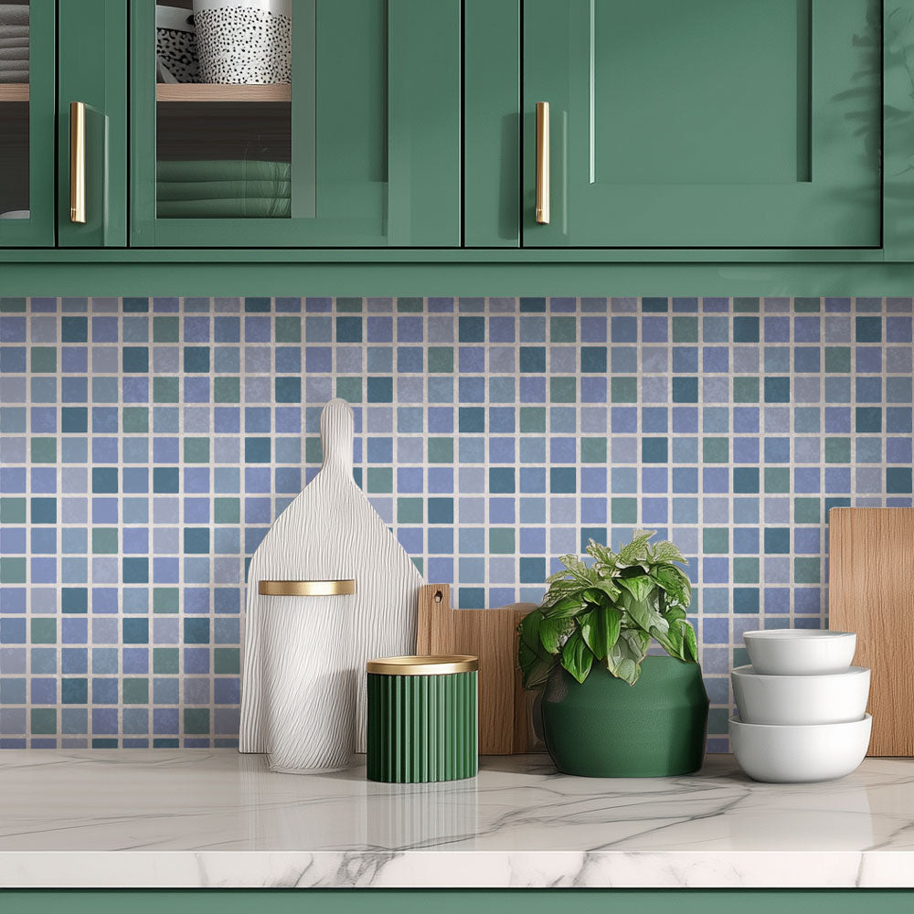 Kitchen interior with green cabinets, stenciled mosaic tile backsplash, and decorative items.