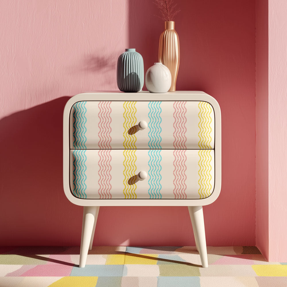 Small dresser with colorful wavy stencil pattern against a pink wall
