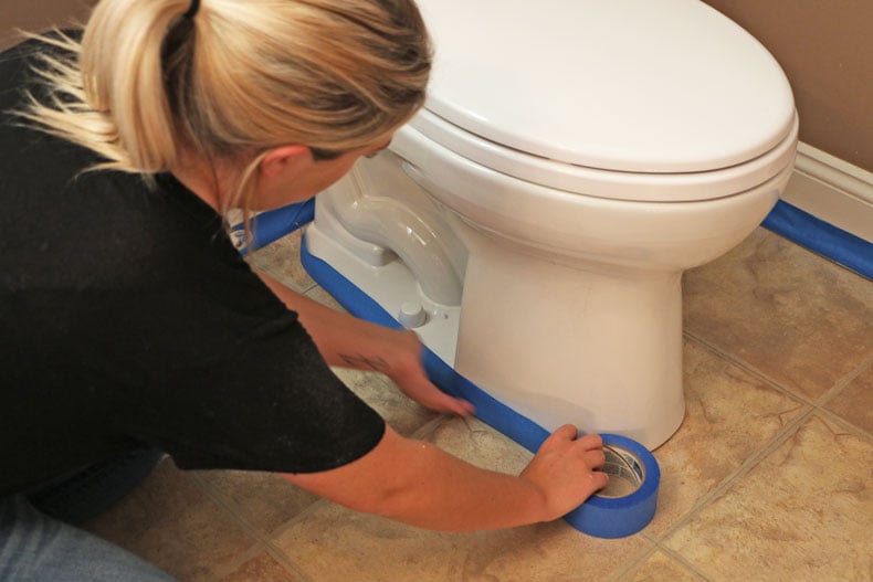 Taping around toilet with blue painters tape