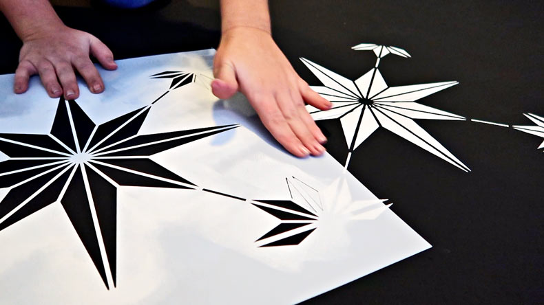 hand placing tile stencil on floor to line up with other painted design