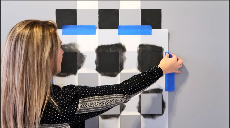 female aligning black and white wall stencil on wall