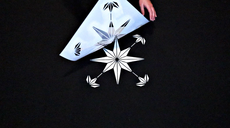 hand pulling star tile stencil off black floor for star design 