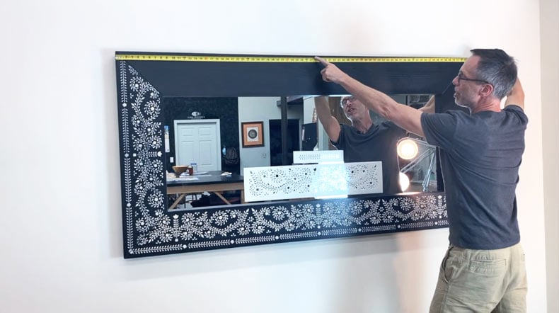 man measuring full length black mirror with inlay stencil design