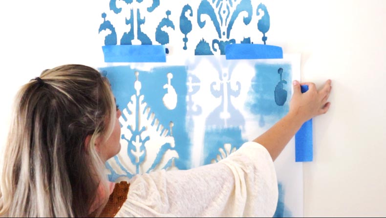 female putting ikat wall stencil on wall