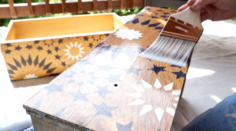 paint brush adding clear coat to wood drawer with moroccan tile stencil