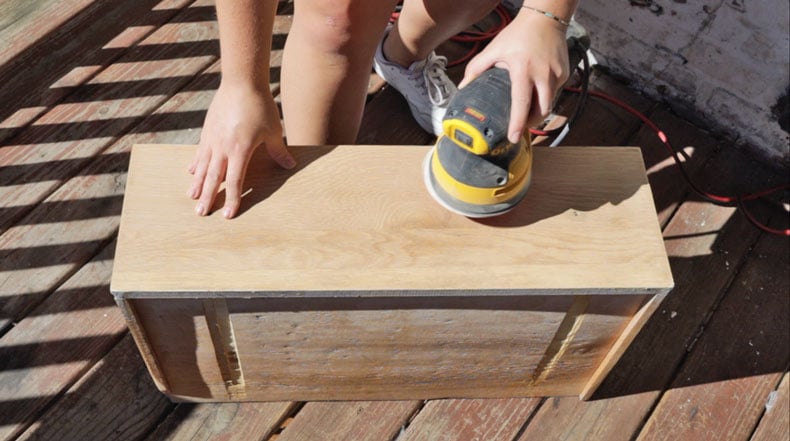 girl using power sander on wood drawer