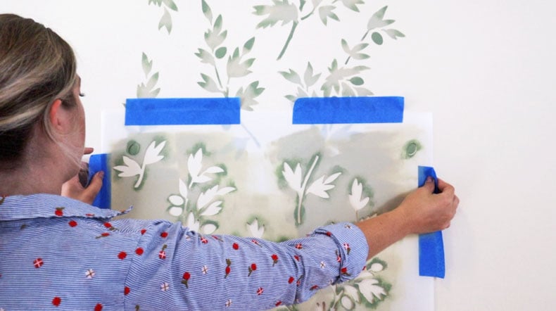 girl aligning farmhouse wall stencil on white wall