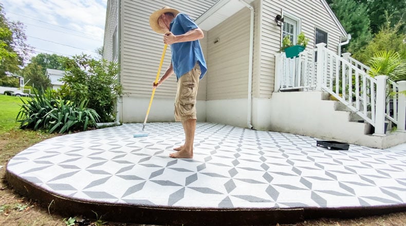 man adding clear coat to patio