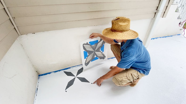 man stenciling tiles with grey paint