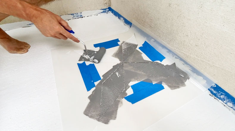 man stenciling tiles with paint roller