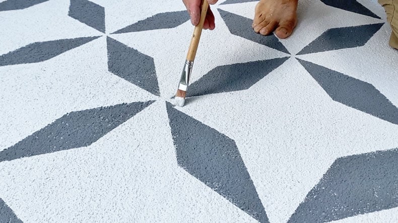 man touching up stenciled tiles