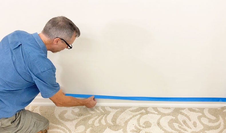 man adding tape before painting
