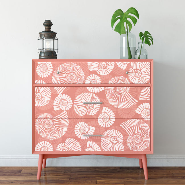 Pink dresser with white ammonite shell stencil against a white wall