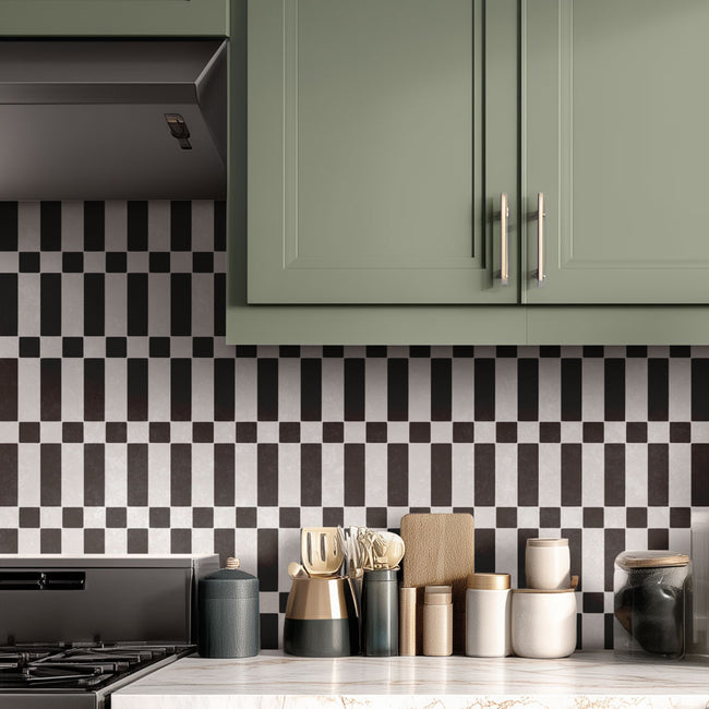 Kitchen with green cabinets, black and white stenciled checkered backsplash, and various kitchen items on the counter.