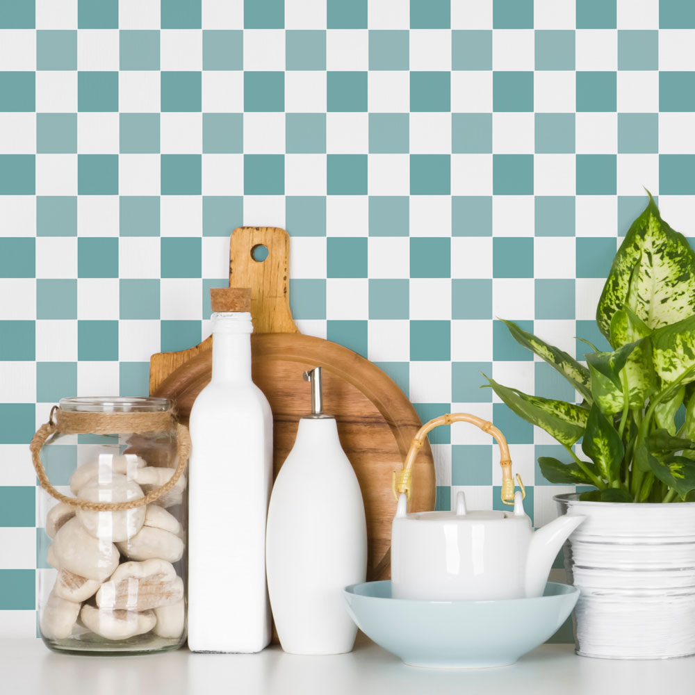 Decorative setting with white bottles, a teapot, a bowl, a cutting board, and a plant against a checkered wall.