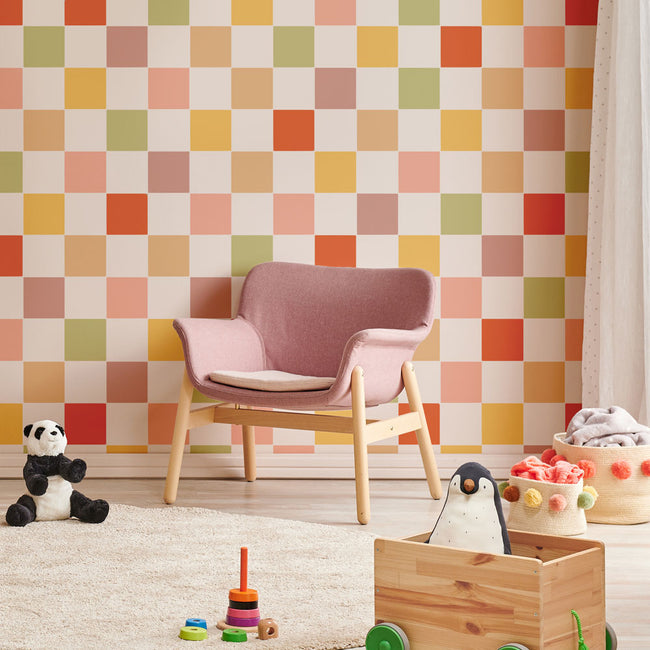 Children's room with a pink chair, colorful checkered wall, and toys on the floor.