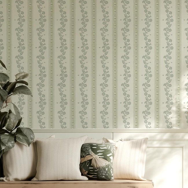 Decorative cottage style floral stripe wall stencil, plant, and pillows on a bench.