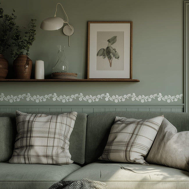 Cozy living room with a gray sofa, plaid cushions, and a framed picture on the wall. stenciled with a carnation border