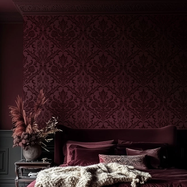 Decorative bedroom with patterned stencil, bed with pillows, and a vase with dried plants.