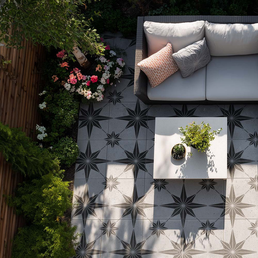 Outdoor concrete patio with a stencil patterned tile floor, white sofa, small table, and decorative plants 