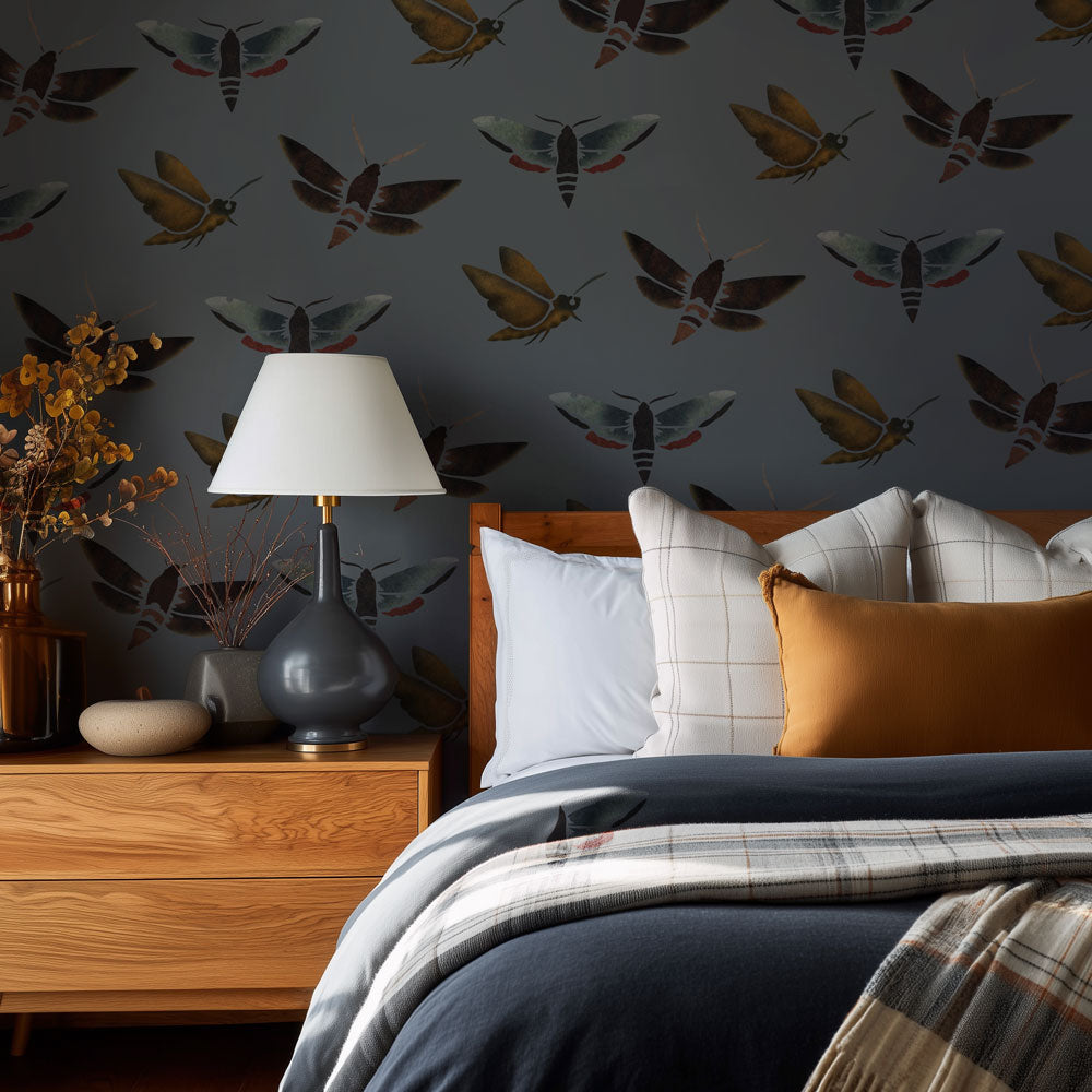 Bedroom with moth-patterned wall stencil, wooden nightstand, and plaid bedding.
