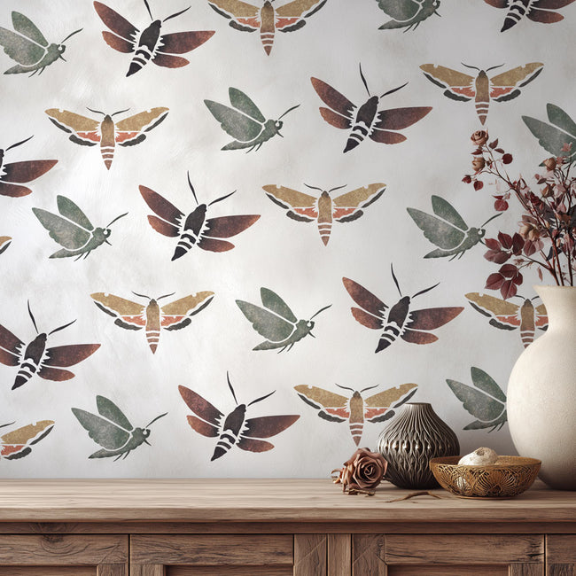 Wall stencil with moth pattern on a wall with decorative bowls and vases