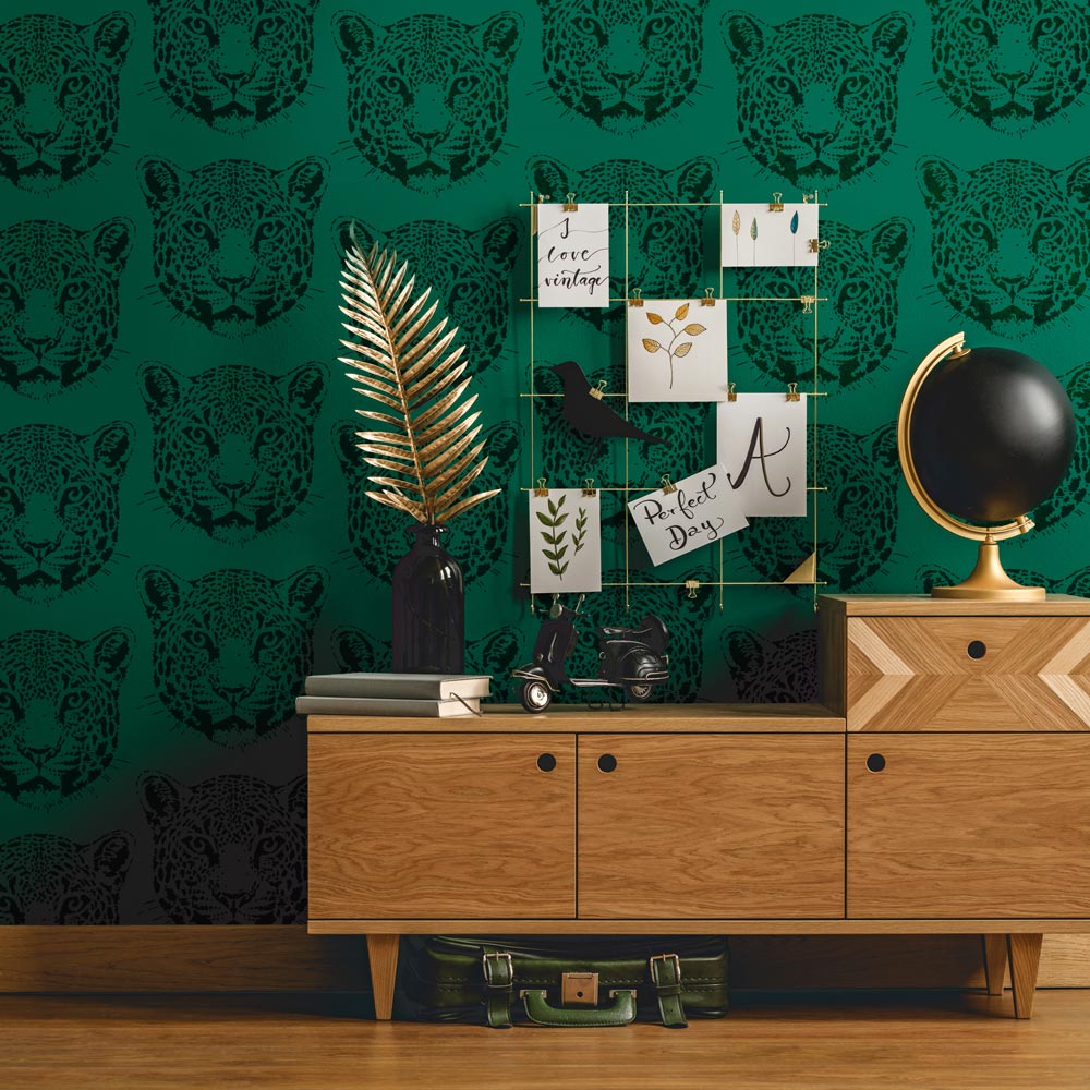 Room interior with wooden dresser against a green wall with jaguar stencil pattern
